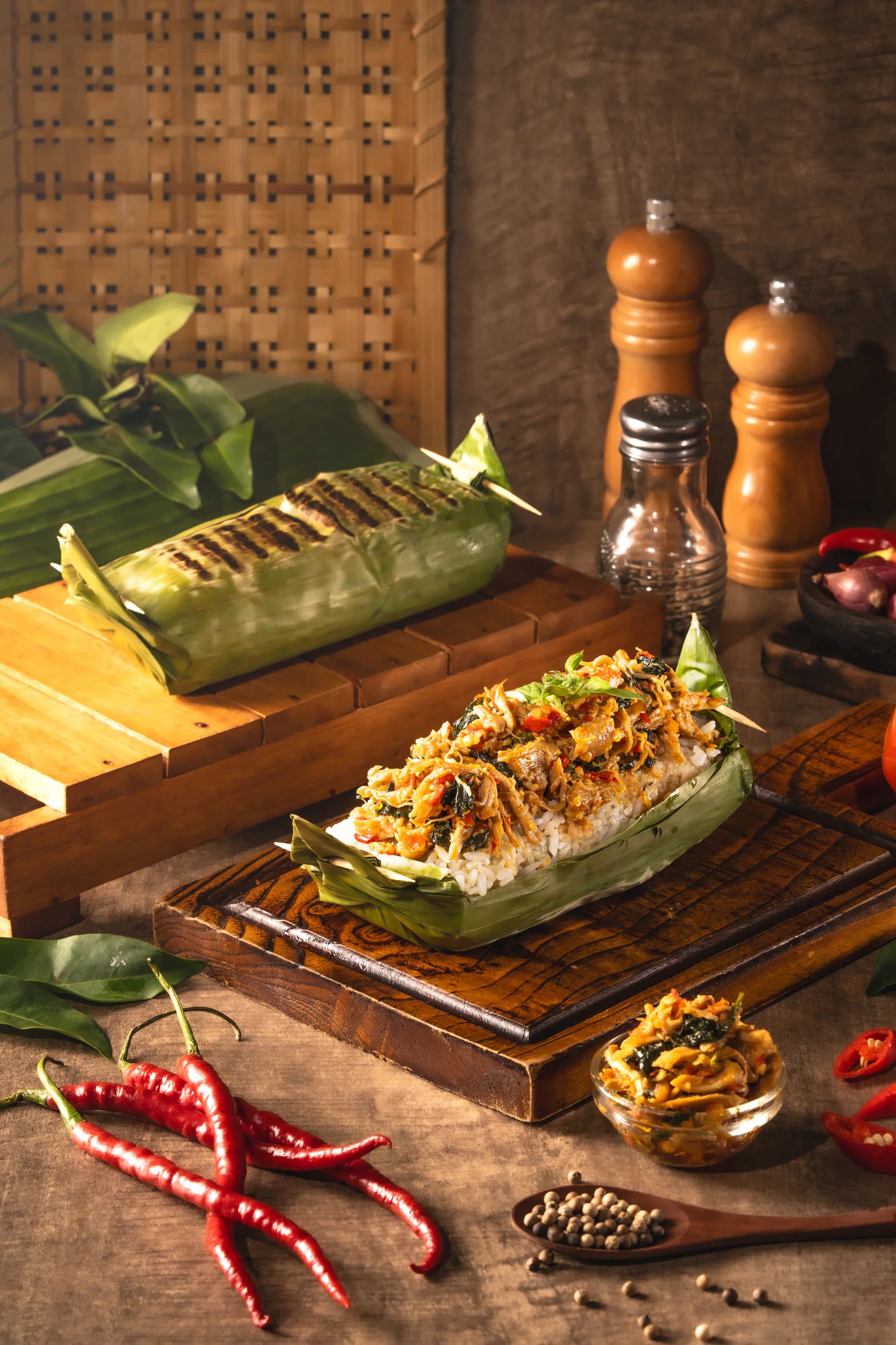 Nasi bakar kemangi Nony terbuka di atas daun pisang, ditemani cabai dan bumbu dapur